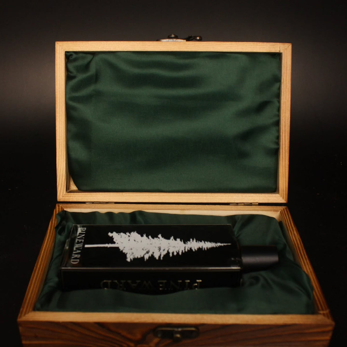 Pineward 100ml bottle lying in the open wooden coffret on green satin